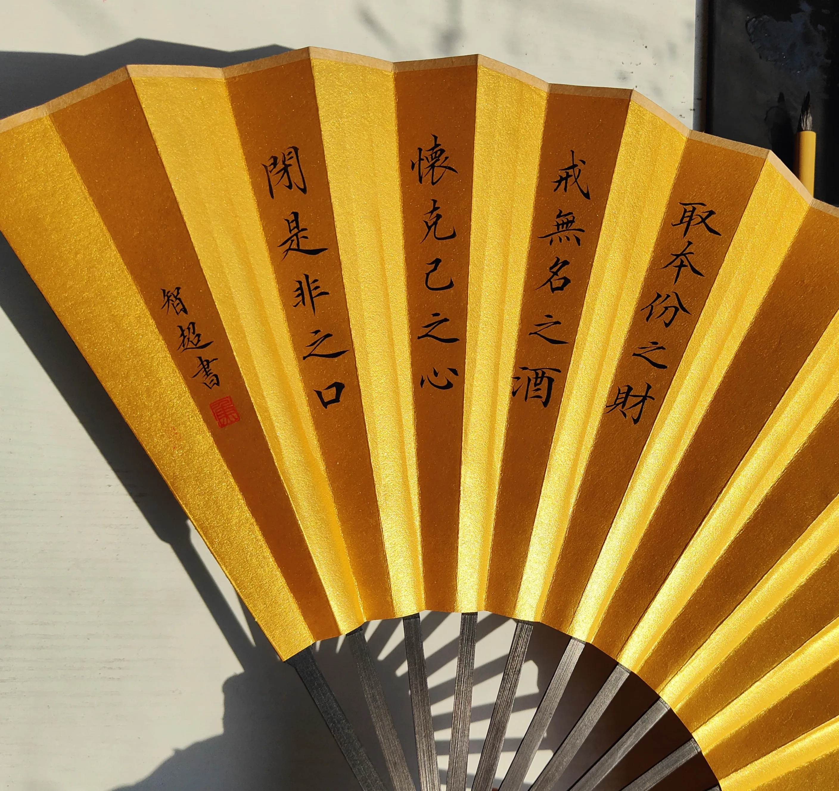 Chinese calligraphy on a gold folding fan