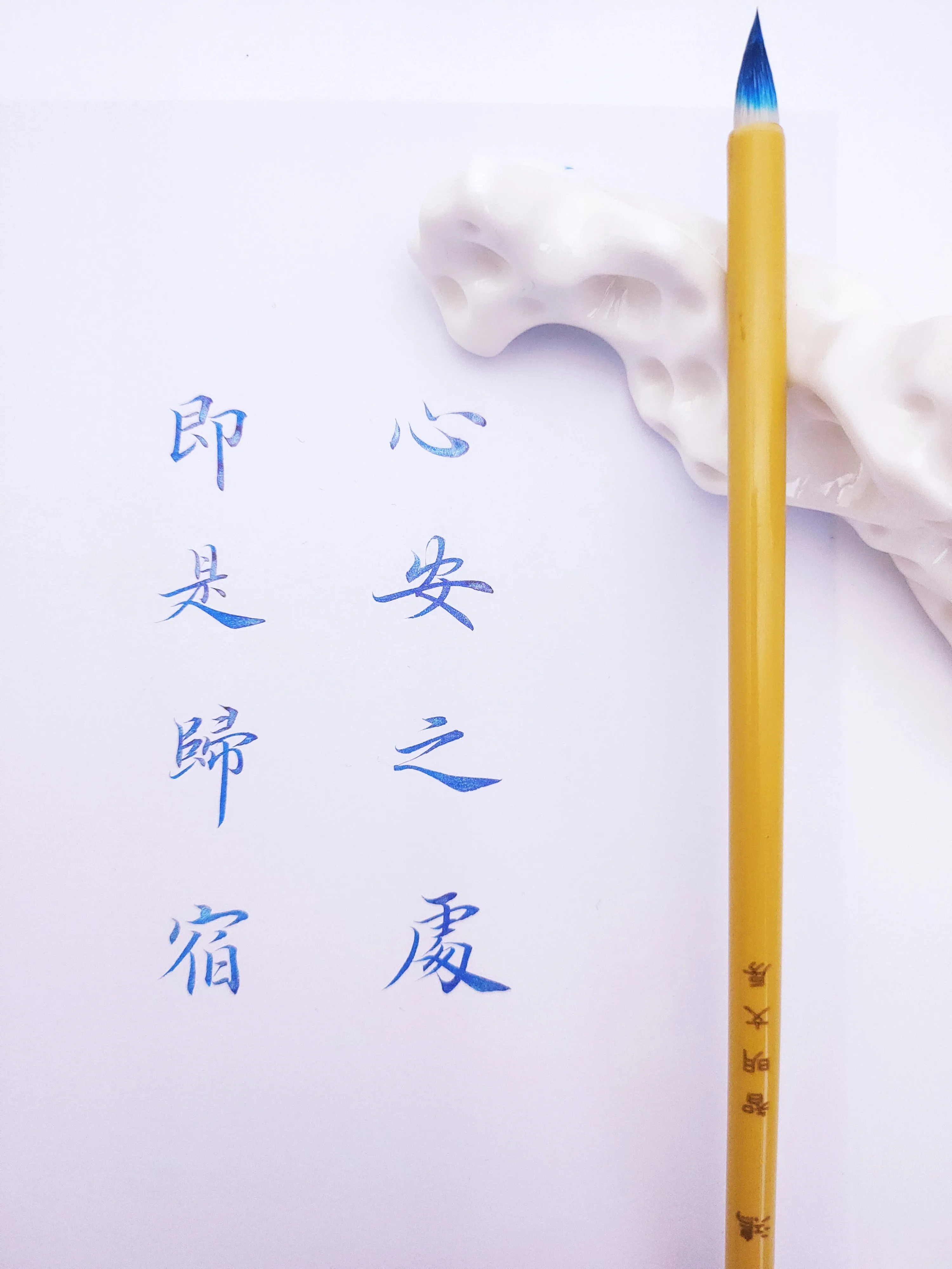 Blue Chinese calligraphy beside a writing brush